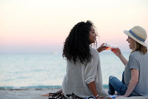 Two woman on a beach toasting with their HaloVino wine tumblers.