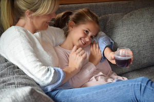 Jessica Bell cuddling on the couch with daughter and holding a HaloVino wine tumbler.