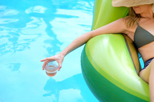 A woman in a pool float holding her HaloVino wine tumbler in the pool.
